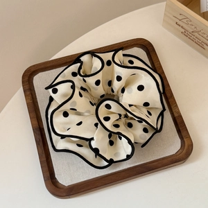 Close-up of beige polka dot scrunchie with black trim in a wooden tray