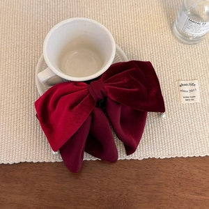 Detail of burgundy velvet bow hair clip with delicate pearl pendants on a ceramic plate