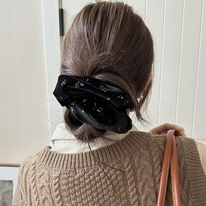 Detail of elegant black velvet hair scrunchie with floral pattern on low bun hairstyle