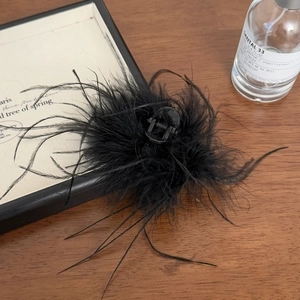 Gros plan détaillé d'une pince à cheveux en plumes noires douces sur fond en bois