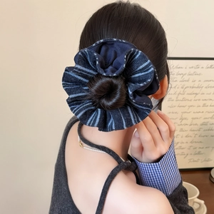 Detail of oversized blue striped scrunchie with rich fabric texture on messy bun hairstyle