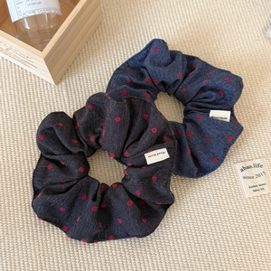 Detail showing denim texture hair scrunchies with red polka dots and handmade label