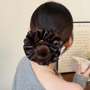 Brown faux leather scrunchie with pleated texture on a woman's hair bun