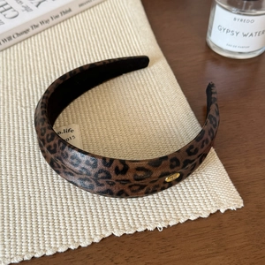 Close-up of leopard print leather headband featuring a gold 'Hand made' metallic label
