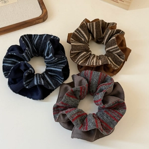 Detailed view of colorful striped knitted scrunchies in navy, brown, and grey colorways