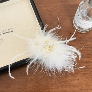 Détail d'une pince à cheveux élégante avec plumes blanches sur fond en bois chaud