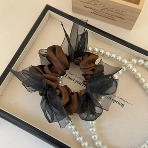 Detail of elegant brown satin hair scrunchie with layered black organza bow and pearls