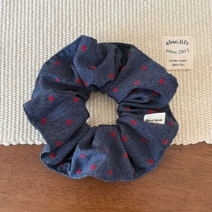 Detail of blue denim scrunchie with red polka dots and white Hand Made textile label