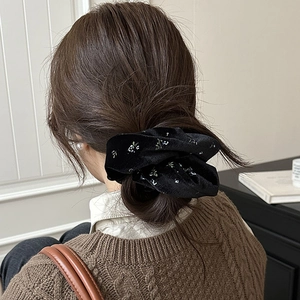 Elegant black velvet floral scrunchie hair tie on model's ponytail for autumn