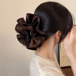 Close-up of a large dark brown satin velvet scrunchie styled on a classic bun hairstyle