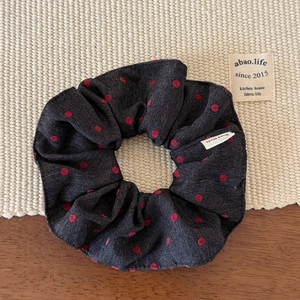 Close-up of denim scrunchie with red polka dots and a handmade fabric label detail