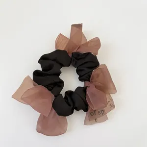 Elegant black scrunchie with pink organza ribbon bows on a clean white background