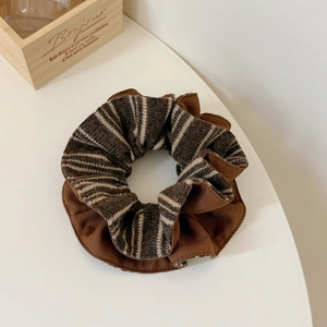Macro shot of brown striped oversized scrunchie on white table with rustic wood decor