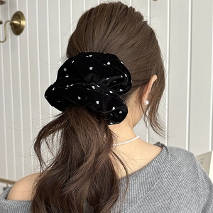 Detail of a large black velvet scrunchie with white heart patterns on a low ponytail