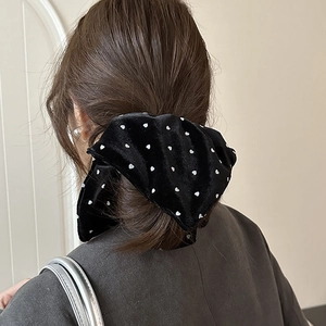 Detail of black velvet scrunchie with white heart pattern tied on a ponytail