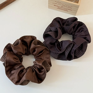 Close-up of brown satin scrunchies with striped inner detail on a white background