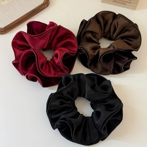 Three oversized velvet scrunchies in wine red, coffee, and black with elegant silk texture