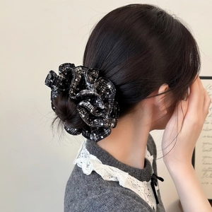 Close-up of black and white plaid scrunchie with polka dots on a stylish hair bun