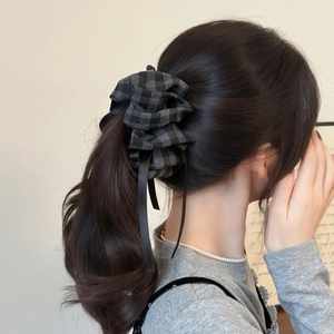 Close-up of elegant plaid fabric banana hair clip with long black ribbons on ponytail