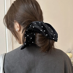 Close-up of a velvet scrunchie with white heart patterns on a low ponytail hair