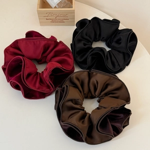 Close-up of velvet and silk scrunchies in burgundy, black, and coffee brown colors