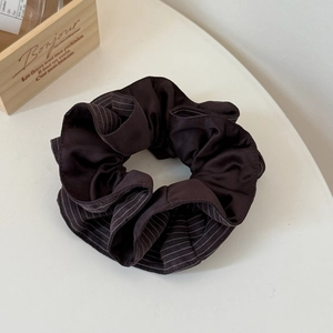 Detailed macro view of dark brown satin scrunchie with subtle white stripe pattern