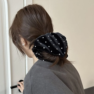 Close-up of black velvet hair scrunchie with white heart pattern on a ponytail