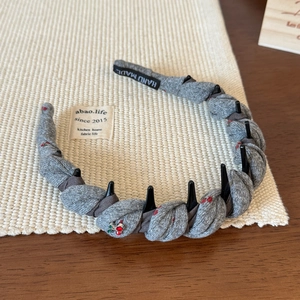 Détail du serre-tête gris avec pendentif cerise montrant les dents antidérapantes