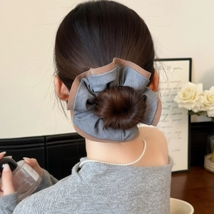 Détail d'un chouchou froncé gris foncé avec bordure contrastée sur un chignon élégant