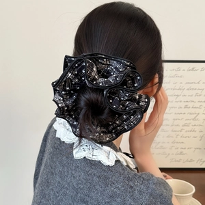 Elegant black and white polka dot tweed scrunchie hair tie shown on a bun hairstyle