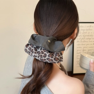 High-quality leopard print and black faux leather scrunchie worn by a model in soft light