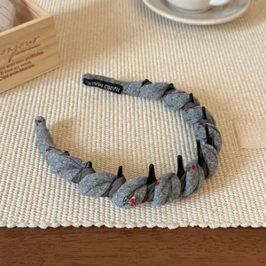 Détail d'un serre-tête tricoté gris avec cerises, peigne antidérapant et étiquette