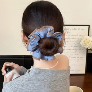 Détail d'un chouchou plissé bleu et marron coiffé en chignon sur les cheveux d'un modèle