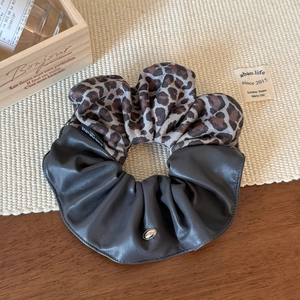Detailed view of leopard print and PU leather hair scrunchie with metal charm
