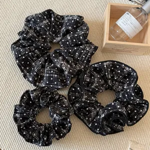 Detailed view of three black and white plaid polka dot scrunchies in various sizes