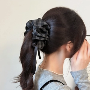 Detail of checkered plaid scrunchie with long black silk ribbons on a ponytail