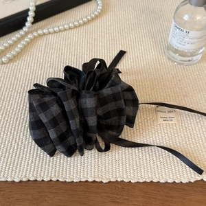 Detailed view of checkered fabric banana clip styled with elegant pearls and perfume