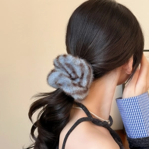 Détail d'un chouchou pelucheux à motif léopard bleu gris sur une queue de cheval