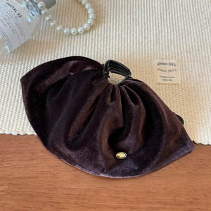 Détail de la pince à cheveux en velours marron avec boucle Wings dorée sur bois
