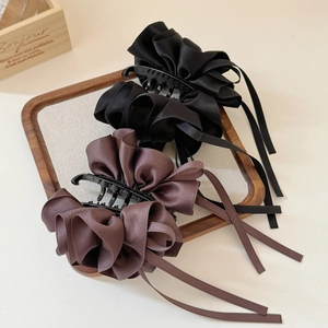 Détail de pinces à cheveux en satin avec rubans plissés sur un plateau à bijoux en bois