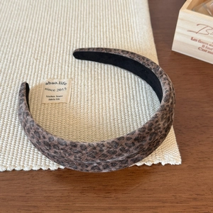 Detailed close-up of a leopard print velvet headband on a textured neutral fabric base