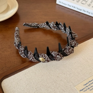 Brown floral twisted headband with non-slip teeth and gold logo detail on vintage desk