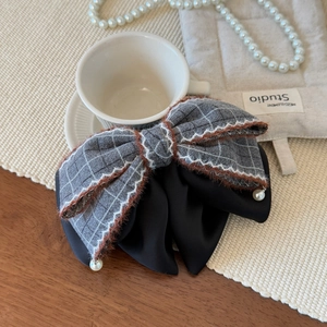 Detail of grey plaid and black satin bow hair clip with plush edges and pearls