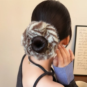 Vue détaillée d'un chouchou en peluche à motif léopard porté sur un chignon flou