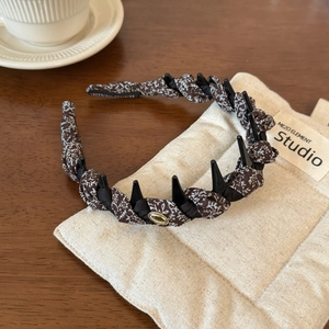 Detail of floral twist headband with non-slip teeth and golden handmade metal logo