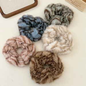 Détail de cinq chouchous en peluche douce aux couleurs d'hiver sur fond beige neutre