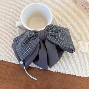 Detail of grey plaid bow hair clip with pearls on a cozy wooden desk setting