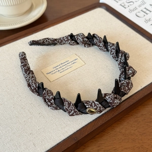 Macro view of woven floral headband featuring anti-slip teeth and vintage gold emblem