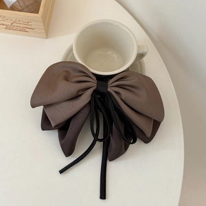 Detail of the multi-layered satin ribbon bow hair claw in dark coffee and black colors