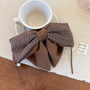 Detail of coffee brown plaid bow hair claw with elegant white pearl pendant accents